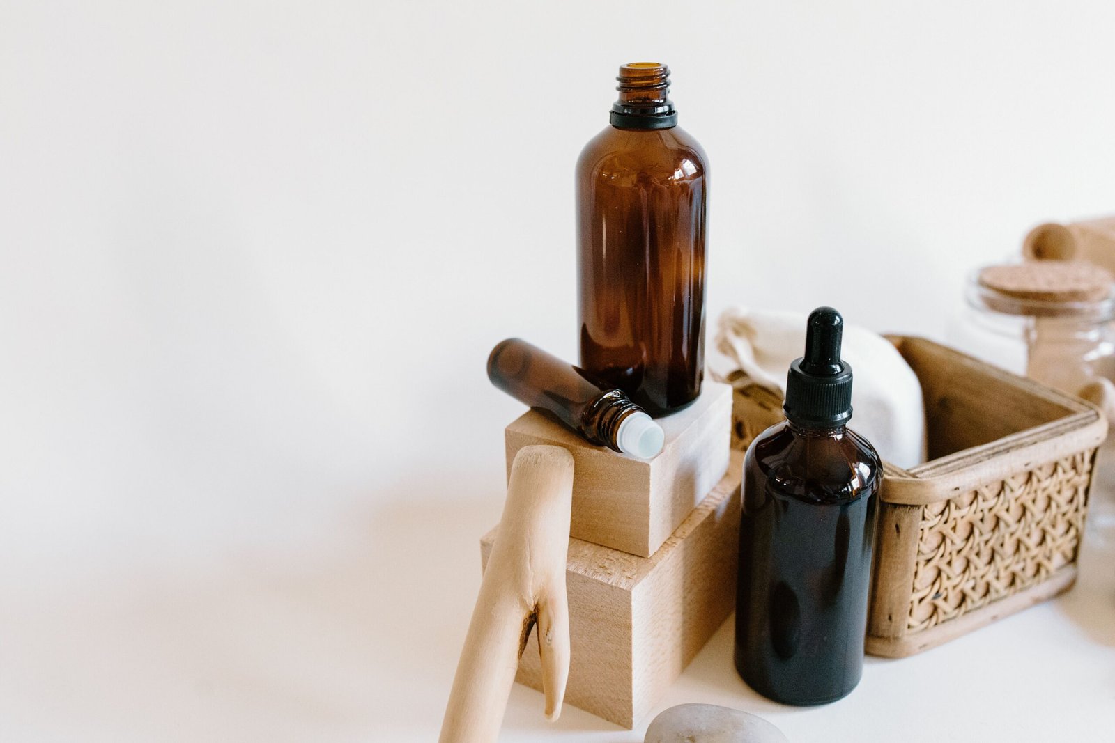 Amber glass bottles with droppers and natural wooden accessories arranged on a light wooden surface.